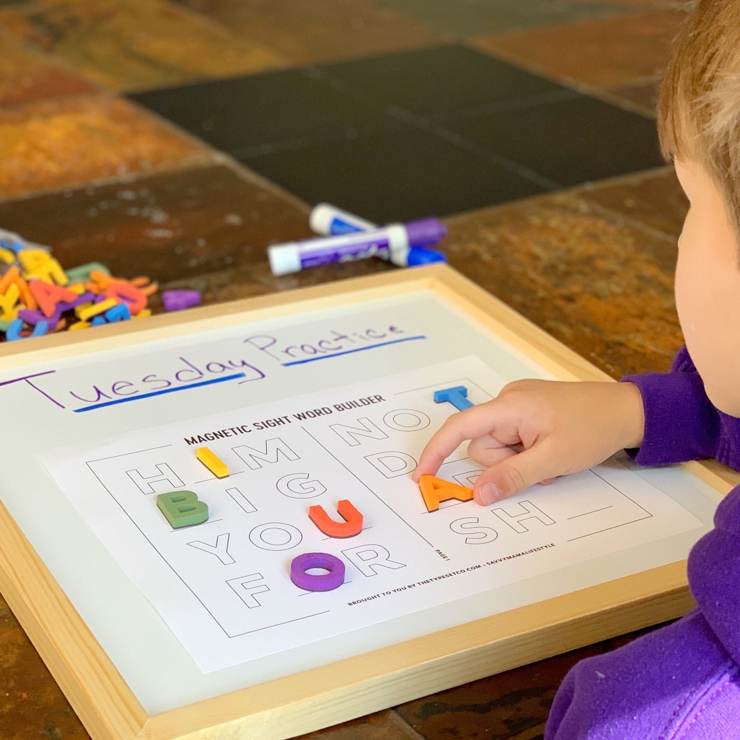 Child playing with magnetic letters on a word-building board.