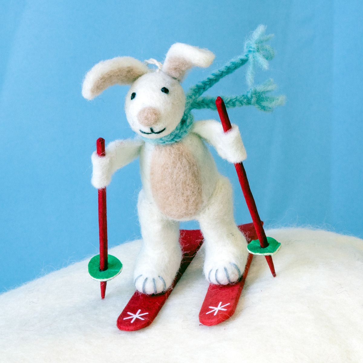 Skiing Bunny with ski poles and a green scarf against a blue background