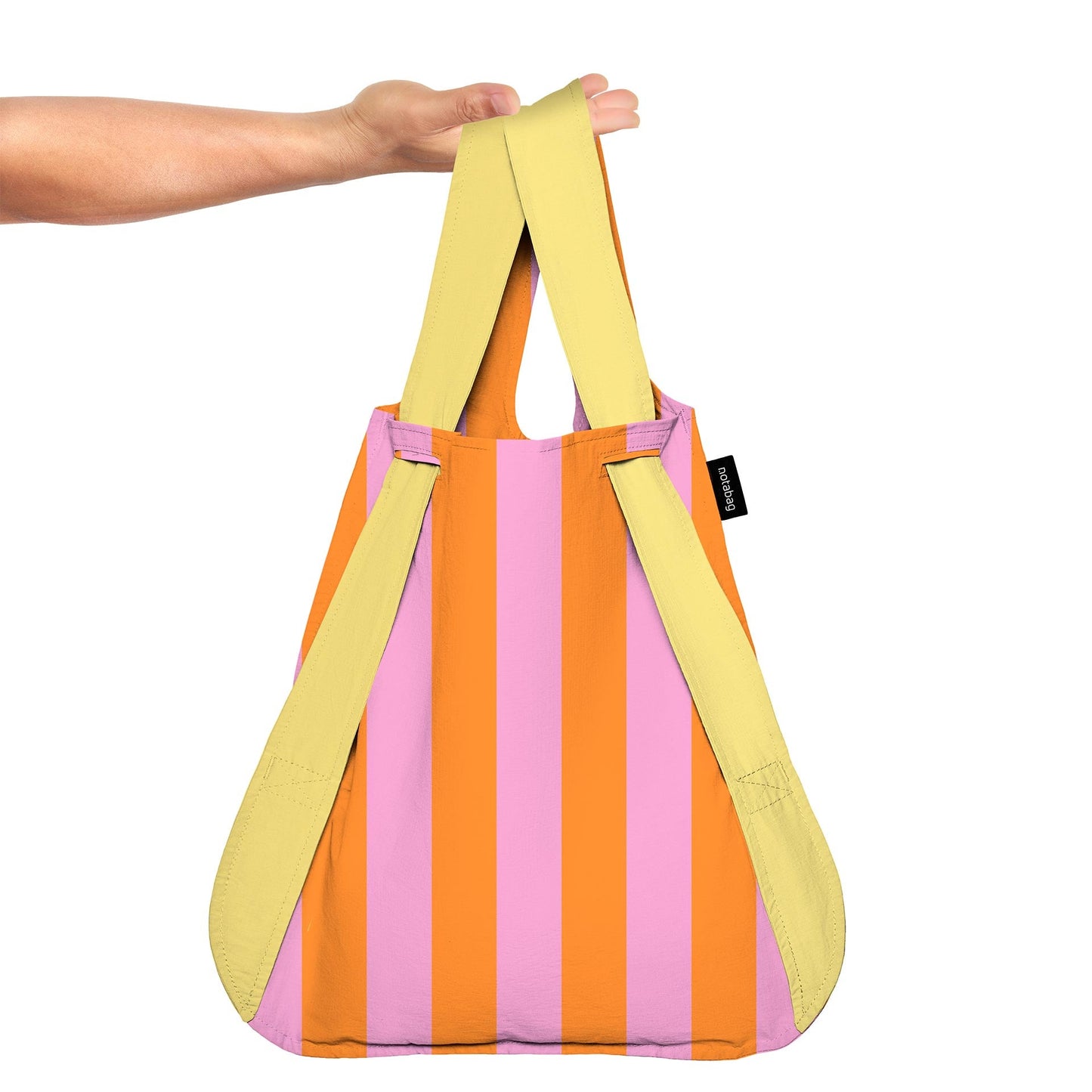 Colorful striped bag with yellow handles held by a person on a white background
