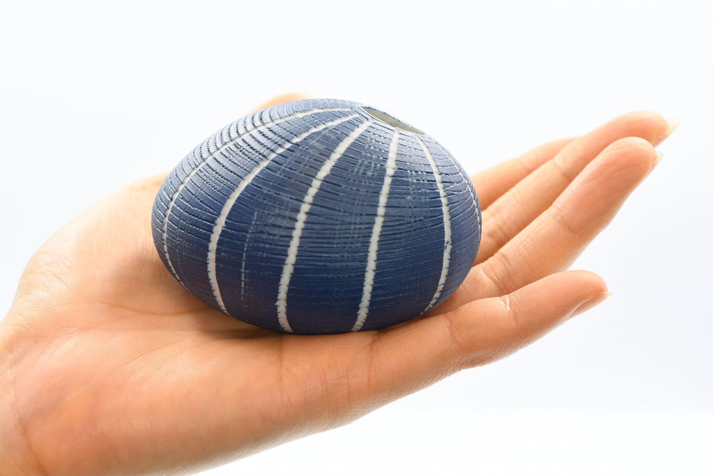 Blue textured vase held in a hand against a white background