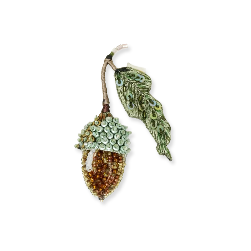 Decorative acorn and leaf brooch on a white background