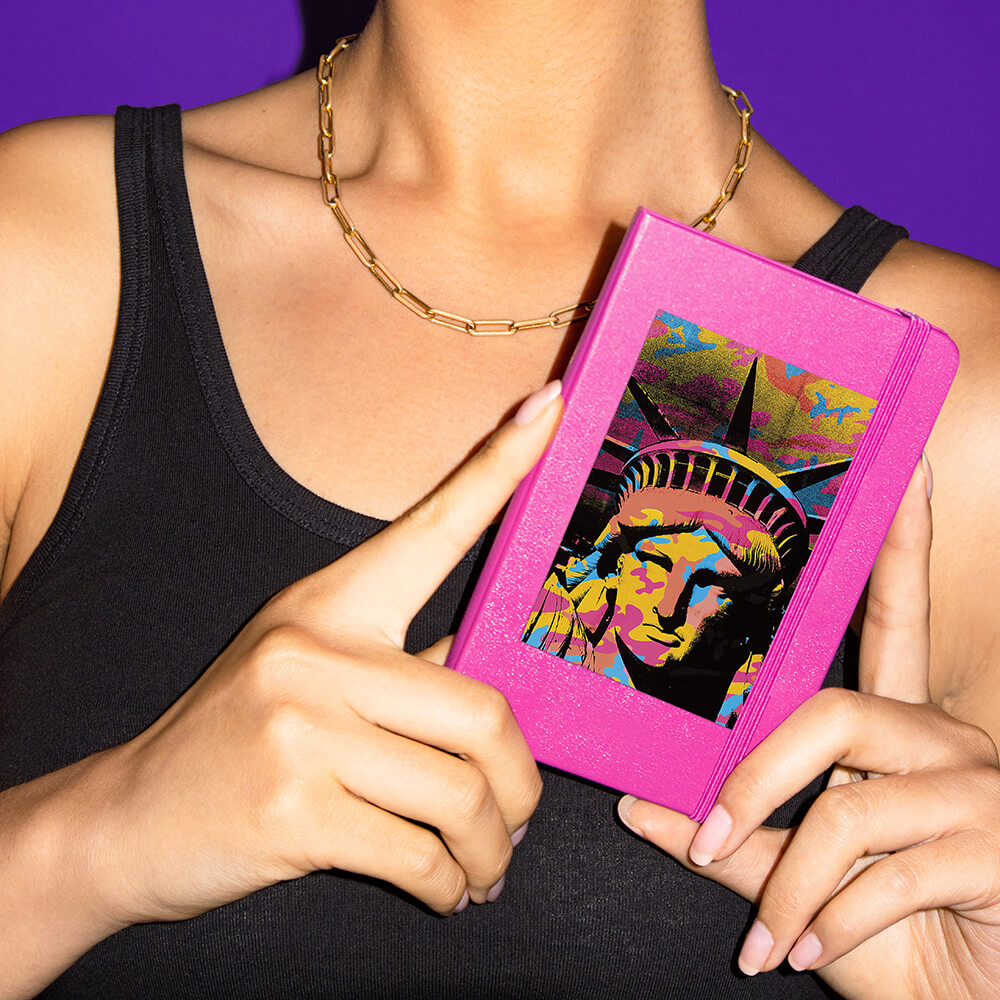 Woman holding a notebook, with a sticker of the stature of liberty on it.