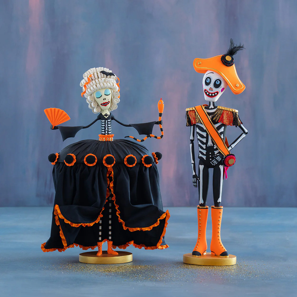 Two decorative skeleton figures with orange and black accents on a blue background
