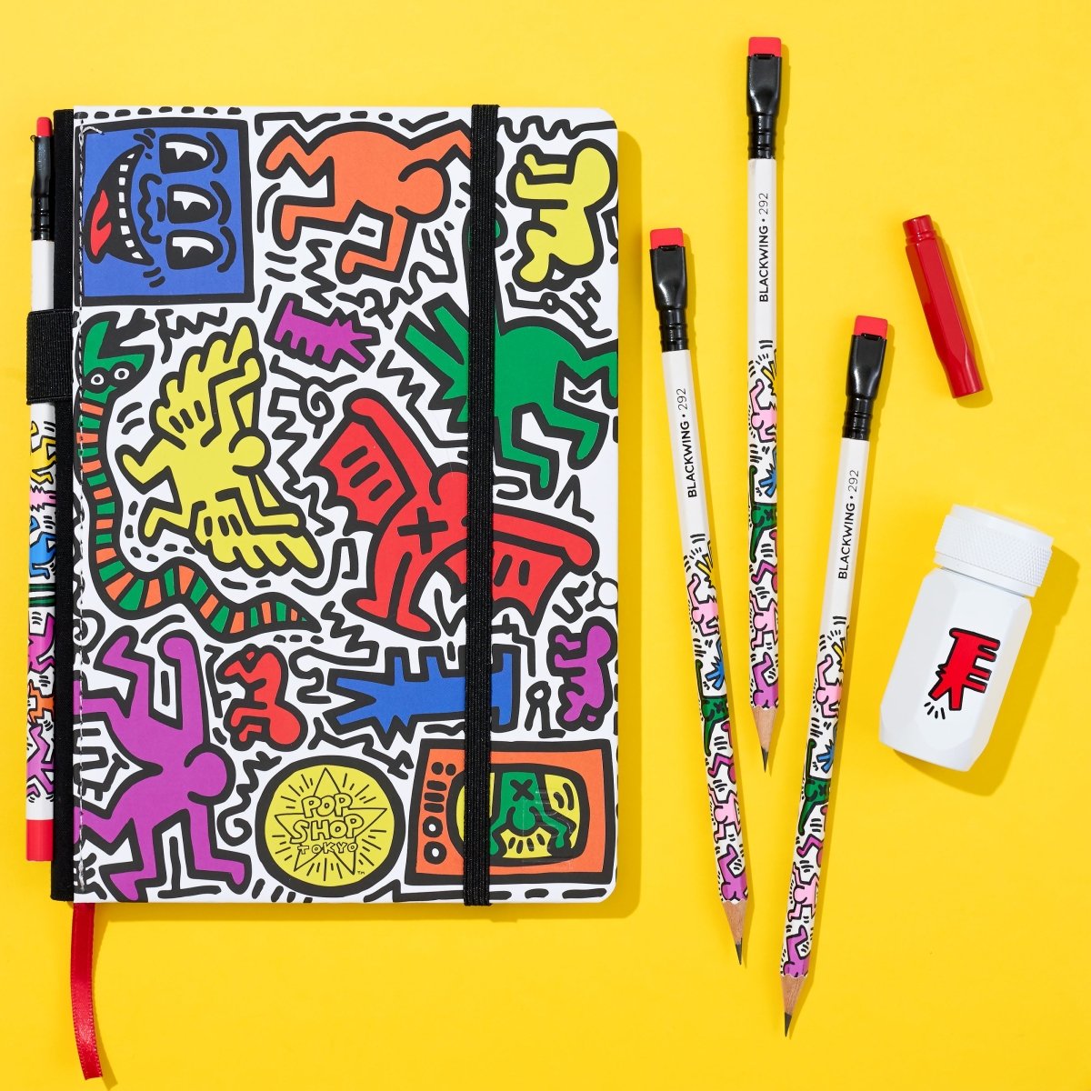 Colorful notebook with art design, pencils, and a sharpener on a yellow background
