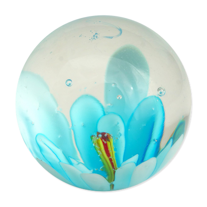 Round glass marble with blue floral design and small figure on a white background