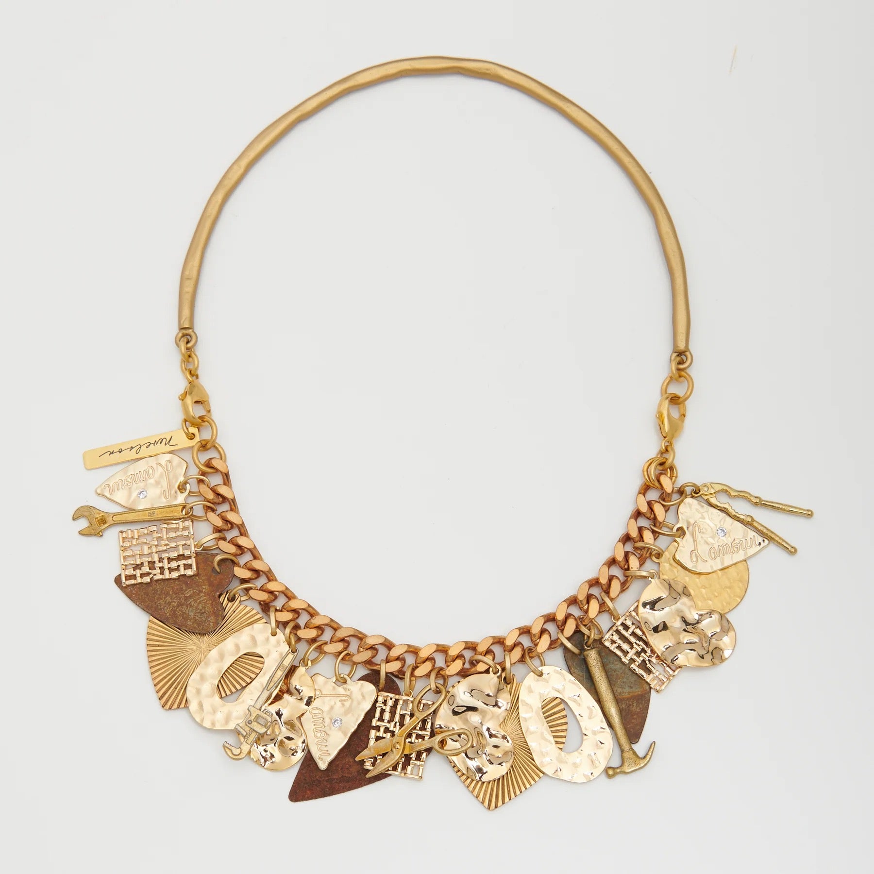 Gold necklace with various charms on a light gray background
