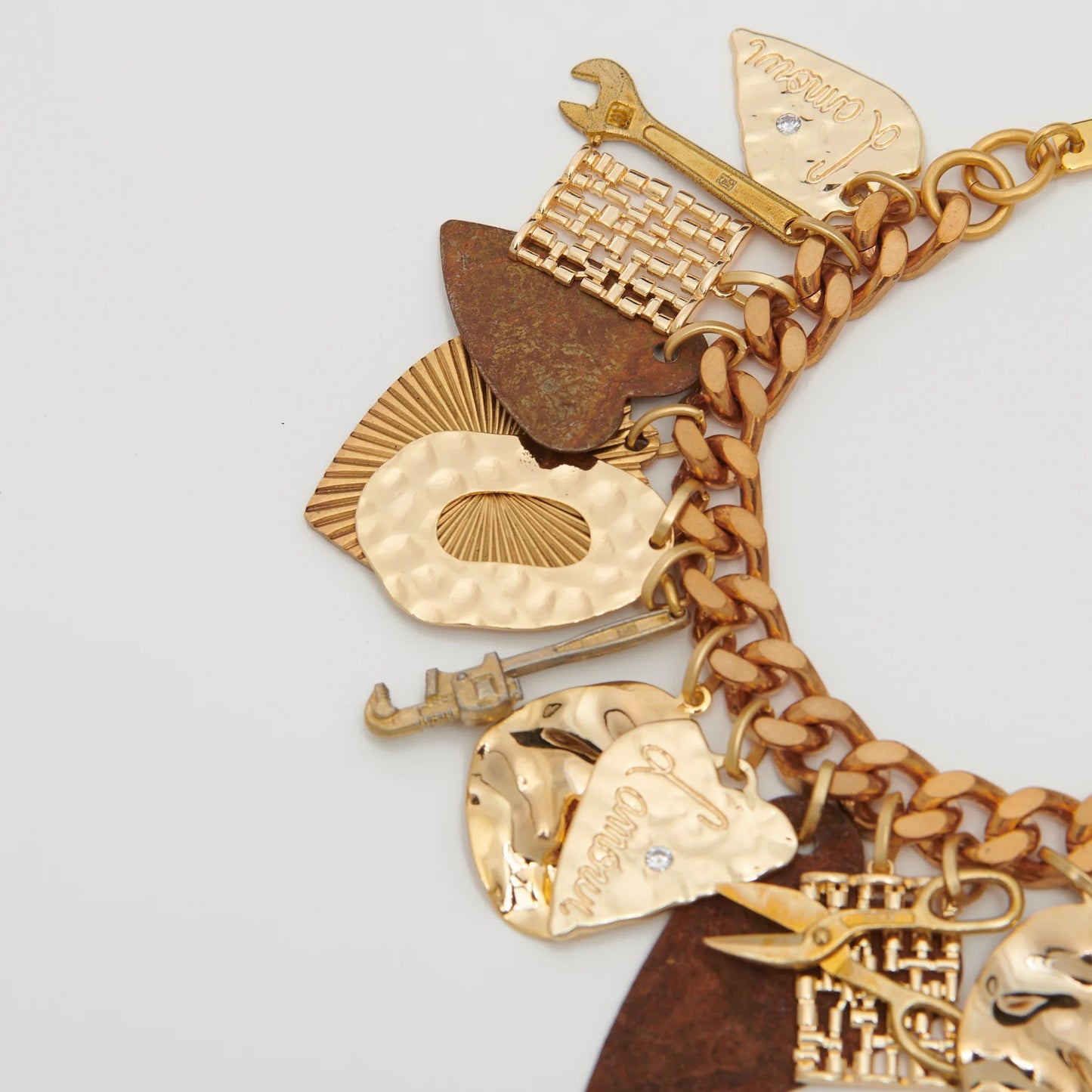 Gold charm bracelet with various charms on a light gray background