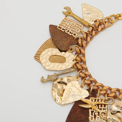 Gold charm bracelet with various charms on a light gray background