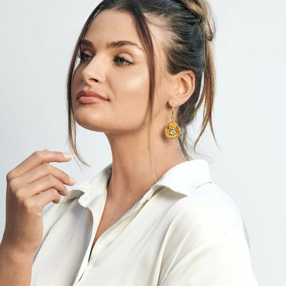 Woman wearing gold earrings with a white shirt on a light gray background