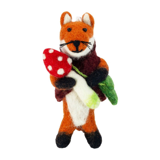 Felt fox ornament holding a red mushroom with white spots on a white background