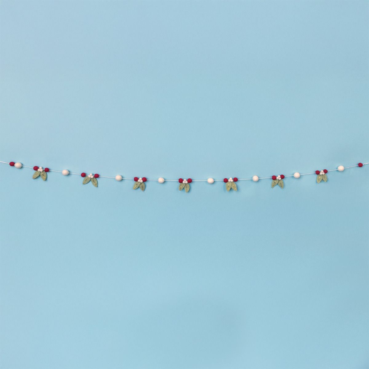 Decorative string with mistletoe and berries on a light blue background