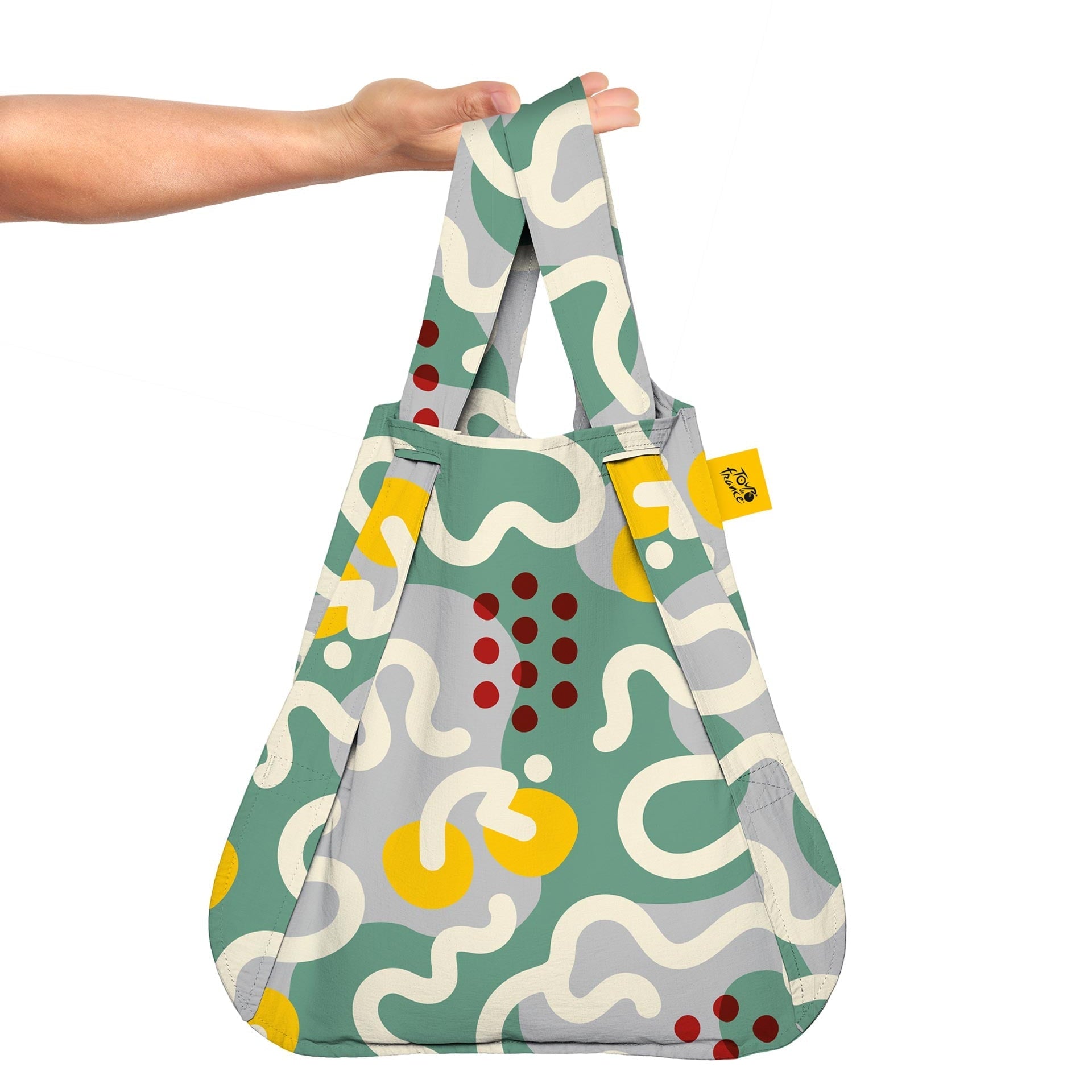 Patterned reusable bag held by a hand on a white background