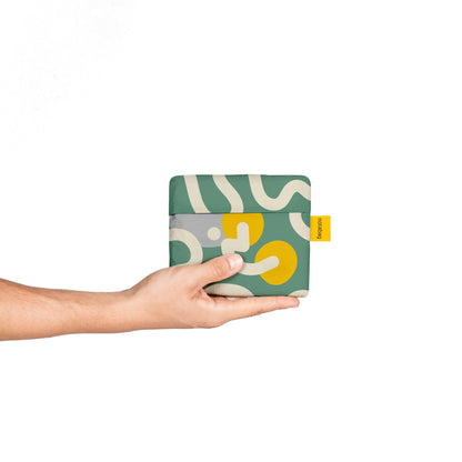 Hand holding a patterned wallet with a visible brand tag on a white background