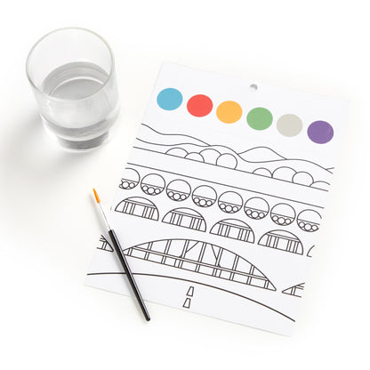 Coloring sheet with a bridge design, colored circles, and a glass of water on a white surface.
