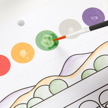 Colorful watercolor circles on a white paper with a brush adding green paint.