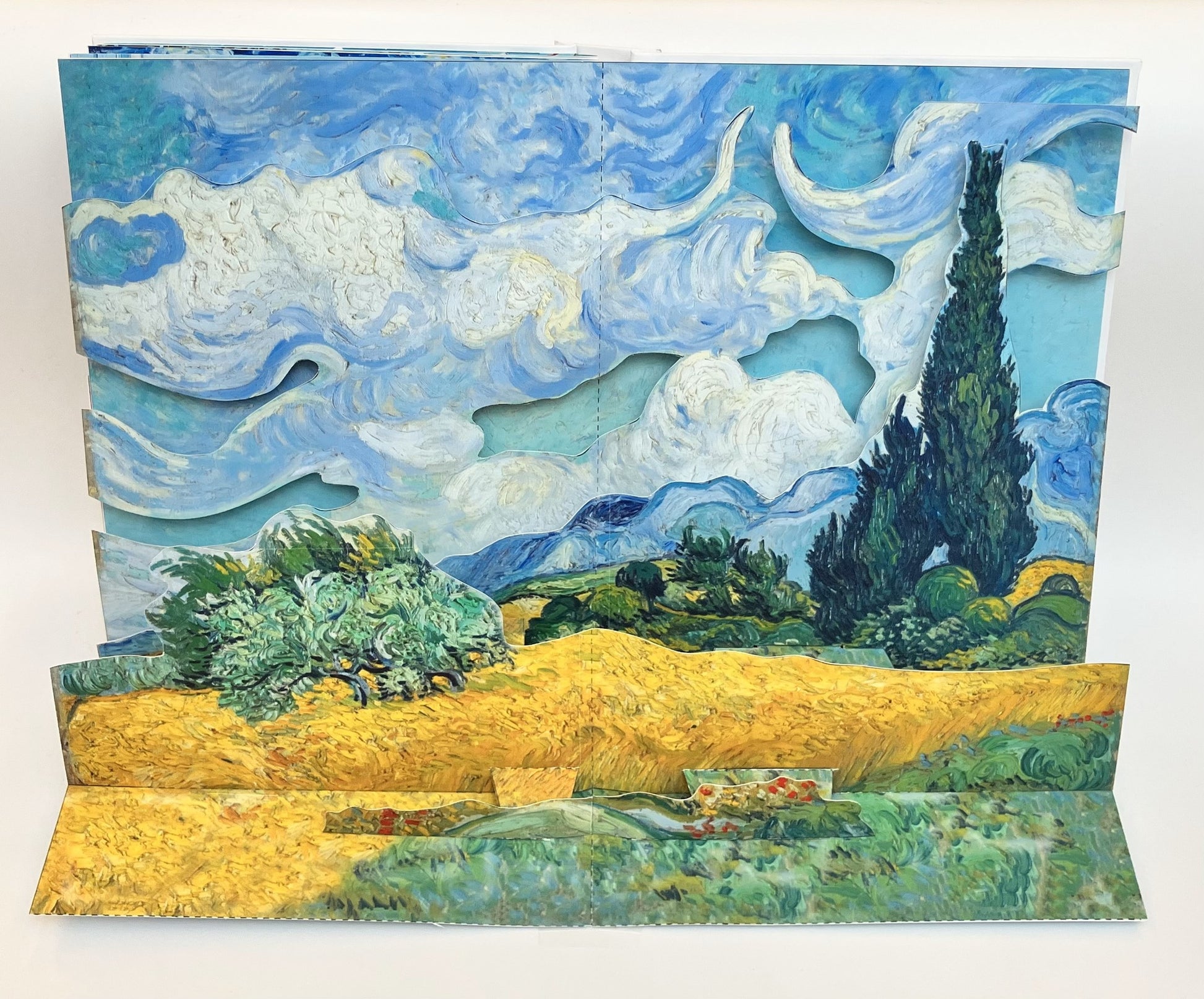 Pop-up book with a landscape design, featuring a yellow field and cypress trees, inspired by Van Gogh.