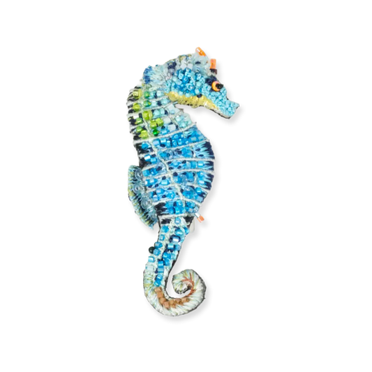 Decorative seahorse figurine with blue and green gemstones on a white background