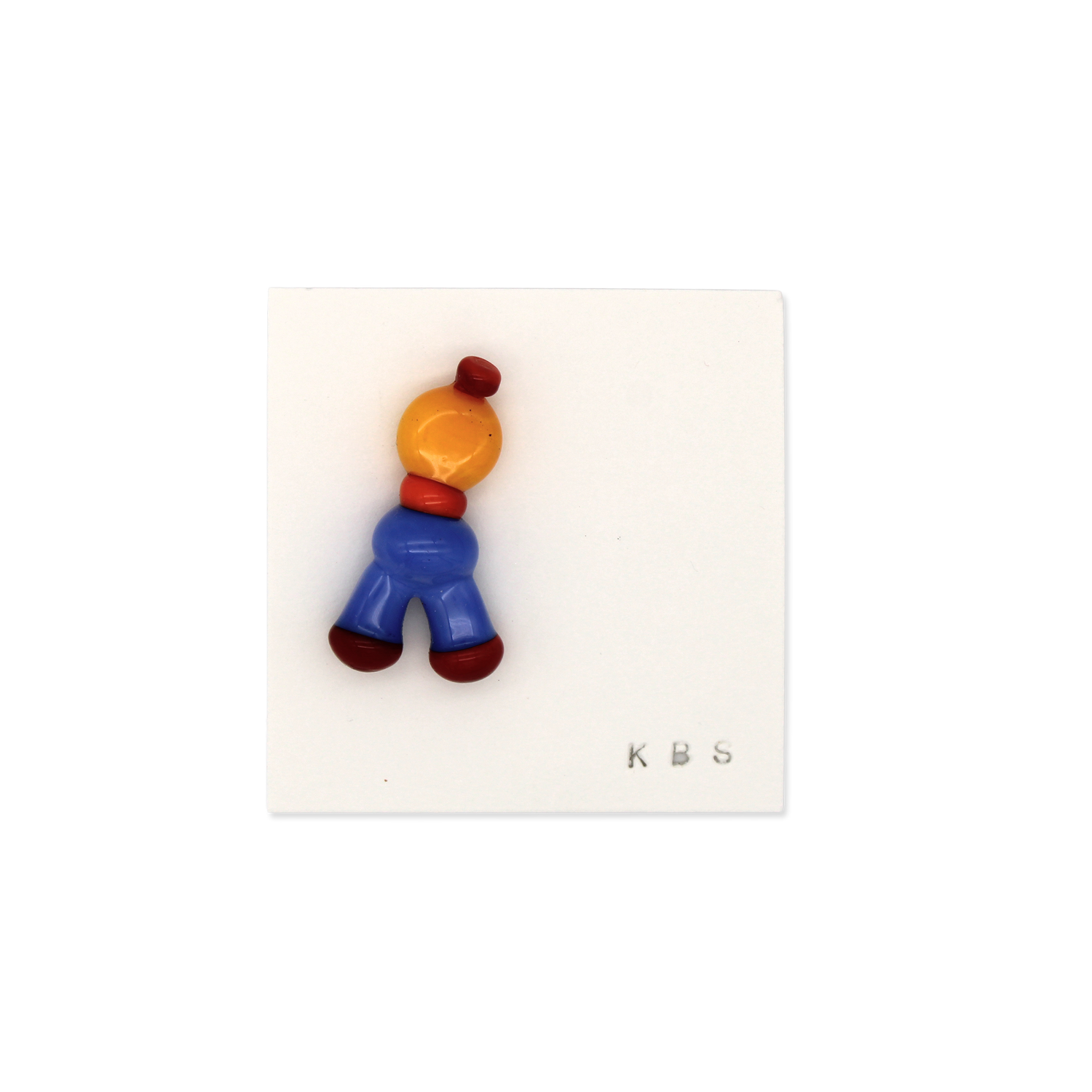 Colorful glass pin/brooch by Krista Bermeo in bright primary colors: red orange, yellow, and blue.