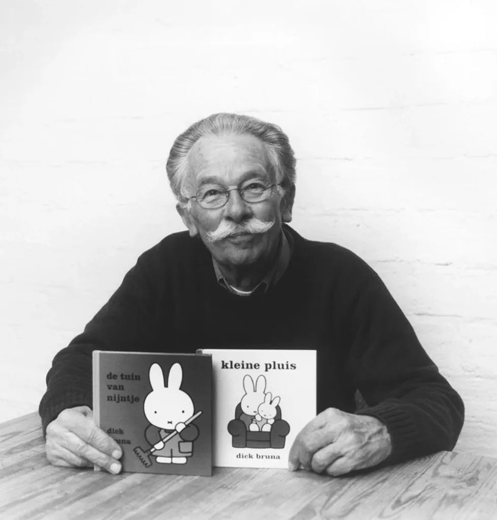 Black and white photo of a man holding two books with rabbit illustrations.