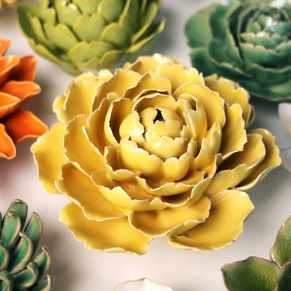 Yellow ceramic flower with green and orange flowers in the background