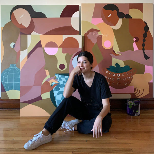 Liz Flores, seated on the floor in front of several of her paintings.