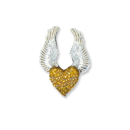 Gold heart brooch with silver wings on a white background