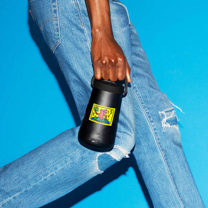 Person carrying a portable speaker emblazoned with a sticker depicting a dog DJ spinning records.