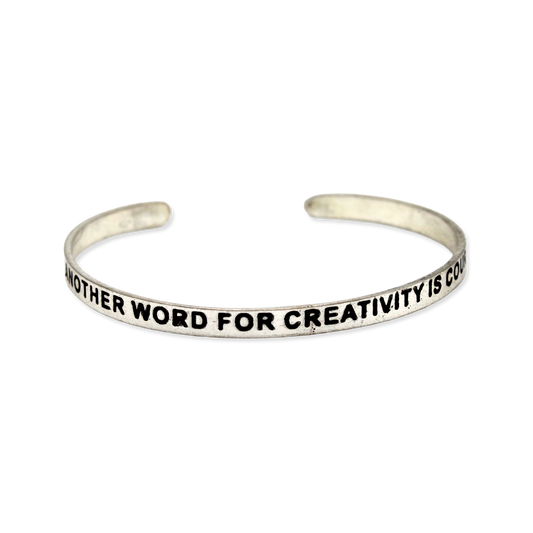 Silver cuff with the motto "Another word for creativity is courage"