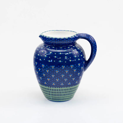 Blue ceramic pitcher with white polka dots on a white background