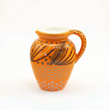 Orange ceramic pitcher with black and white patterns on a white background