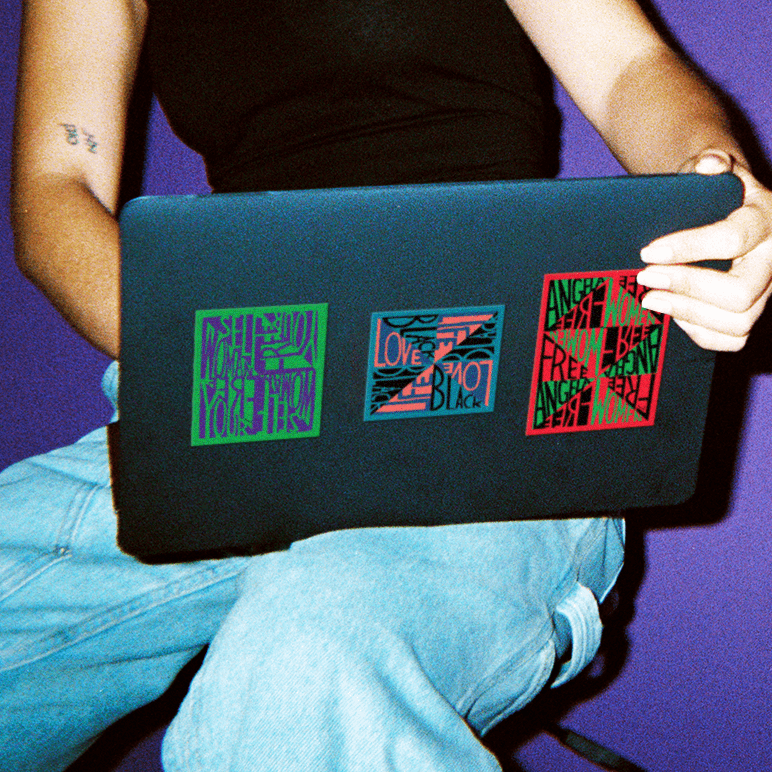 Person with laptop featuring three stickers by Faith Ringgold.