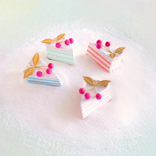 Ornaments shaped like small cake slices with pink berries on a light background