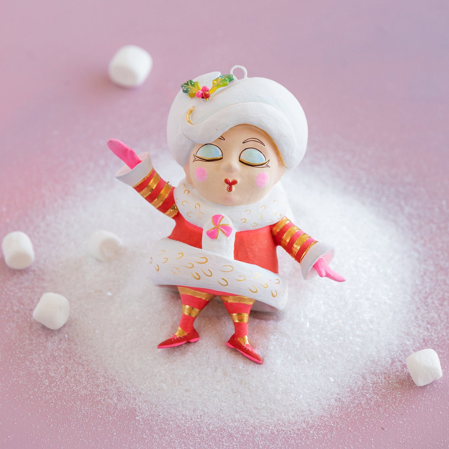 Decorative figurine of a snow maiden surrounded by marshmallows on a pink background