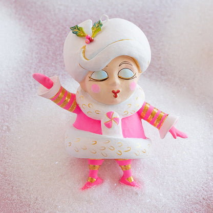 Decorative figurine with a white hat and pink outfit on a textured white background