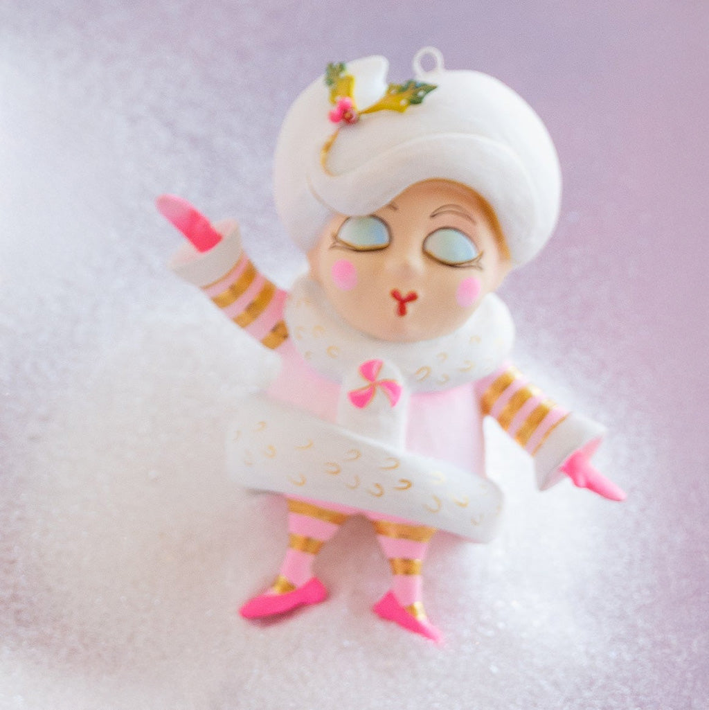 Decorative figurine of a girl in a white outfit with pink accents on a light purple background