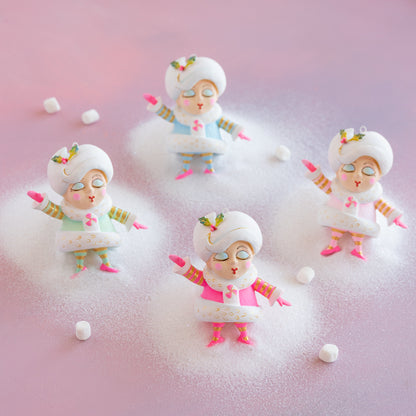 Four small figurines of Madame Noel with colorful accents on a pink and white gradient background.