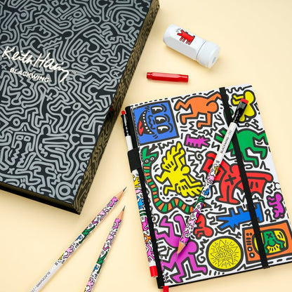 Keith Haring-themed stationery set with notebook, pencils, and eraser on a beige background