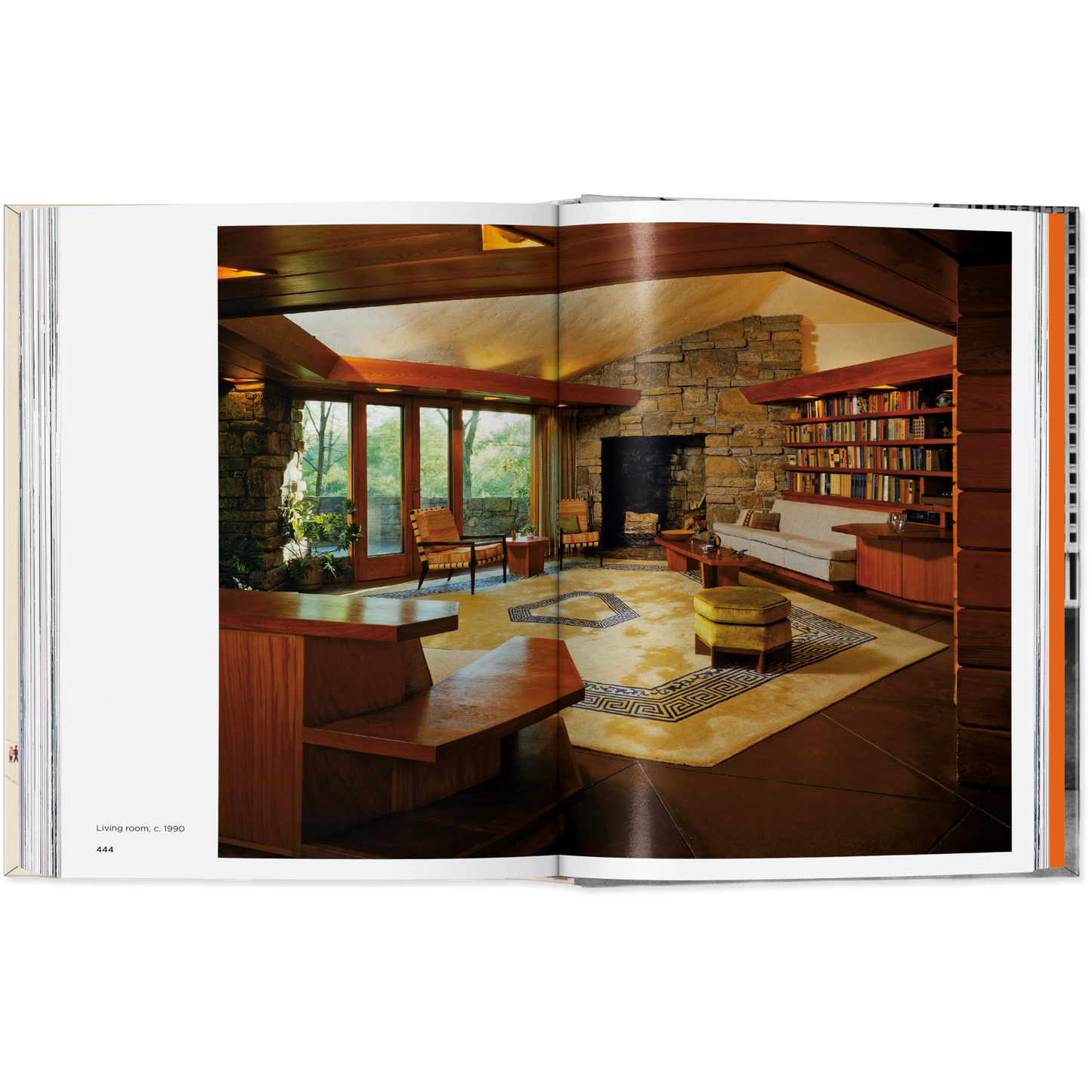 Open book showing a modern living room with a stone wall and bookshelf.