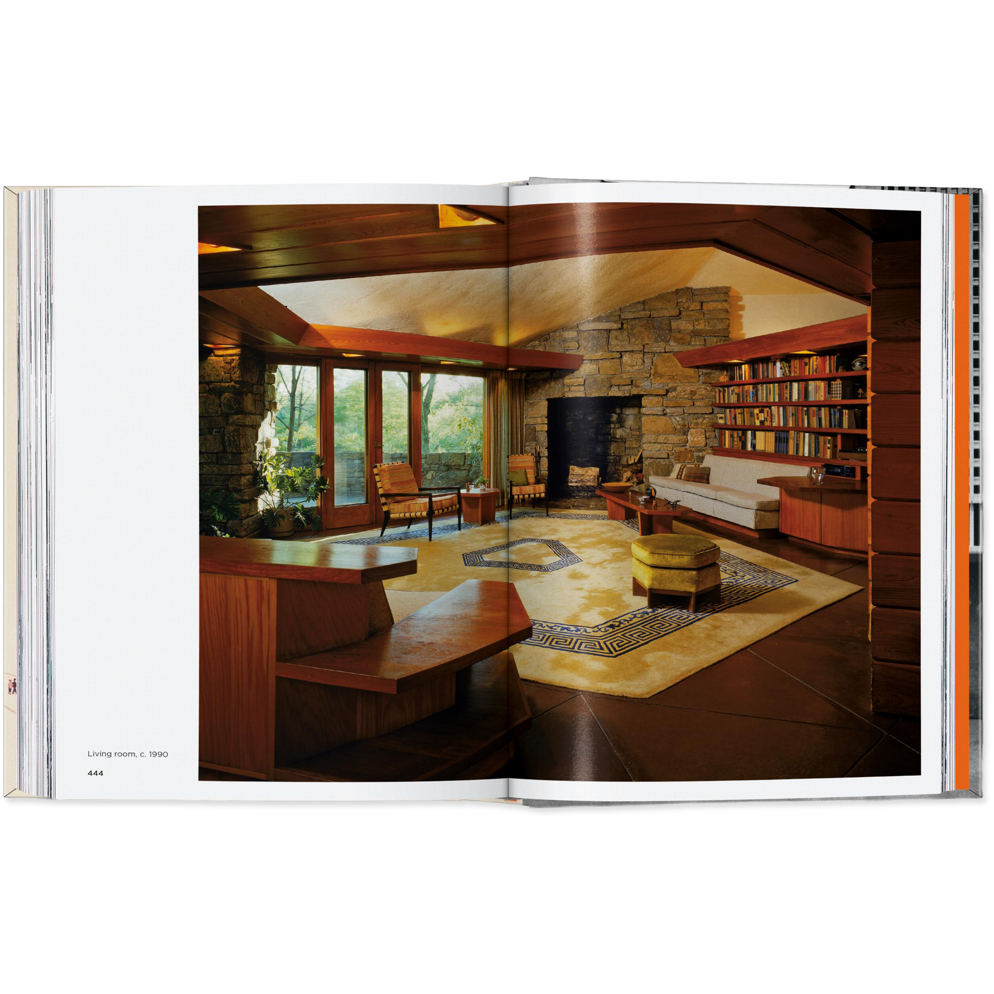 Open book showing a modern living room with a stone wall and bookshelf.