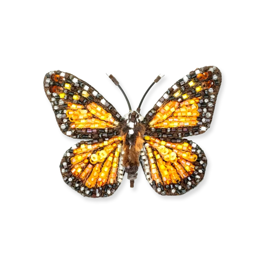 Butterfly-shaped brooch with orange and brown details on a white background