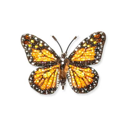 Butterfly-shaped brooch with orange and brown details on a white background