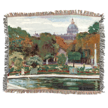 Woven blanket with a scenic landscape design featuring trees, buildings, and a pond.