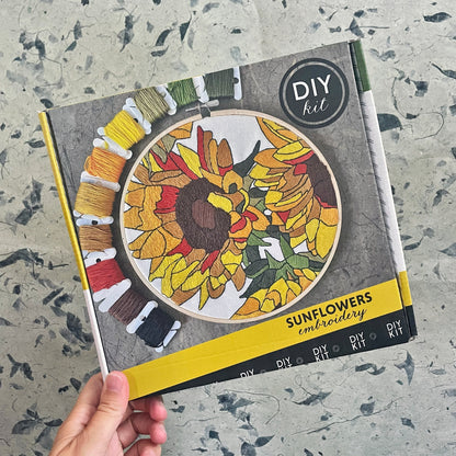 Sunflowers embroidery DIY kit packaging on a textured surface