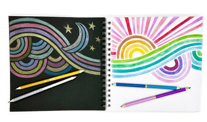 Sketchbook with black and white paper and rainbow designs and pencils on a white background