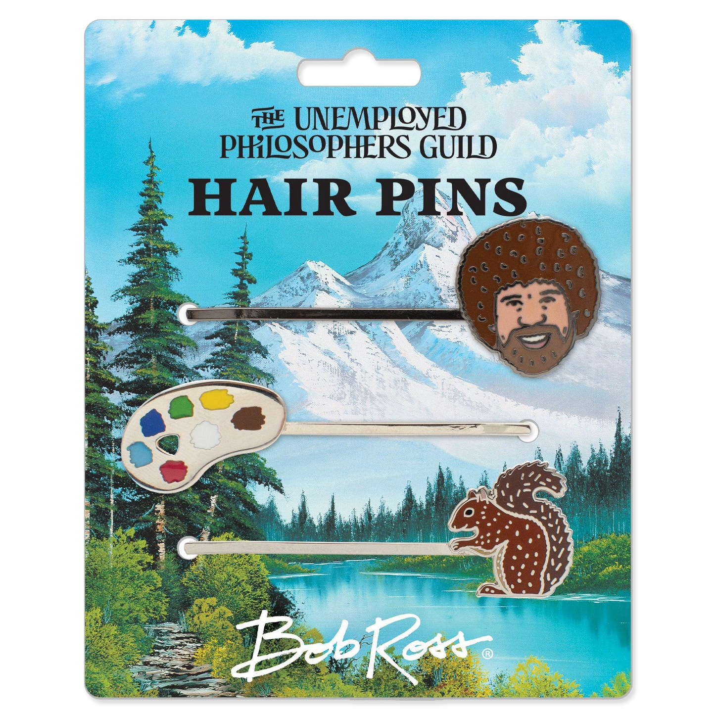 Packaged hair pins with nature-themed designs on a scenic background, featuring 'The Unemployed Philosophers Guild' and 'Bob Ross'.
