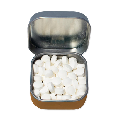 Small open tin filled with white mints on a white background