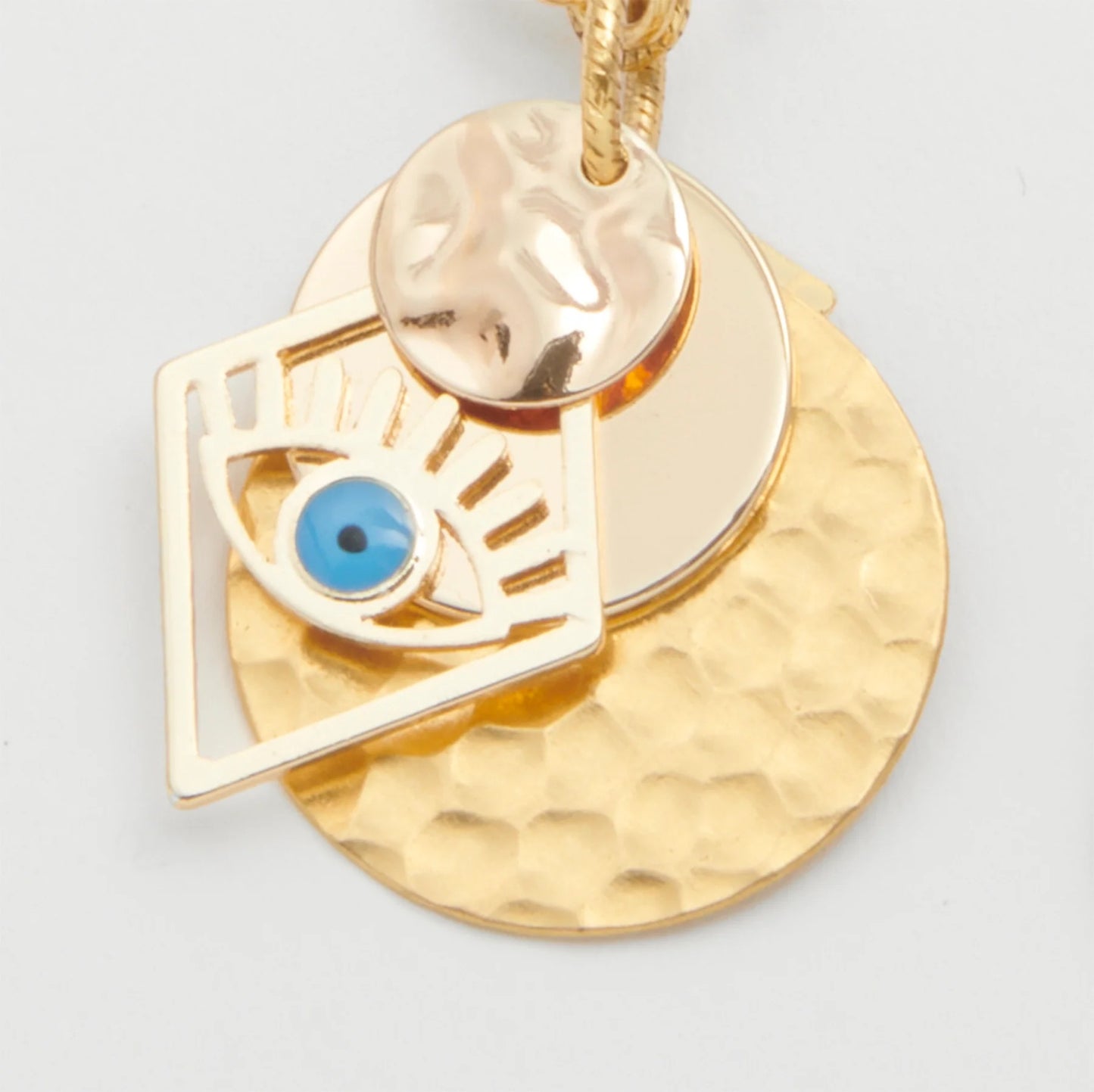 Gold earrings with blue eye design on a light gray background