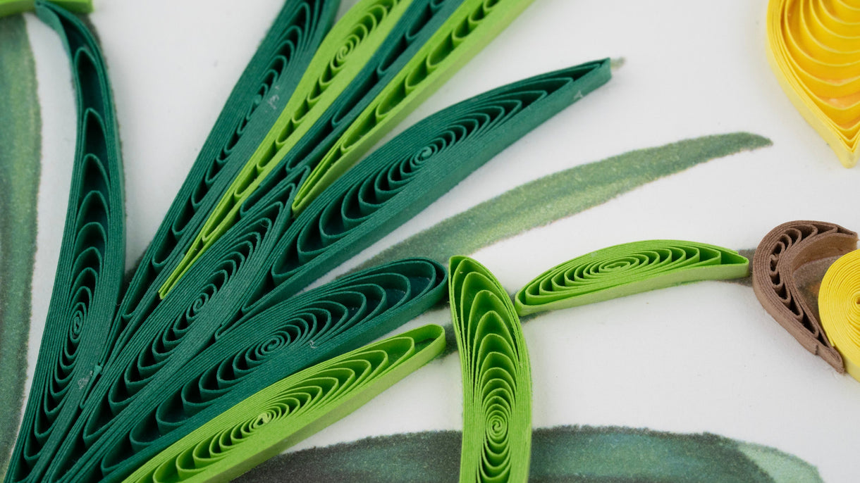Green quilled paper art on a white background with additional colored paper pieces.