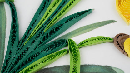 Green quilled paper art on a white background with additional colored paper pieces.