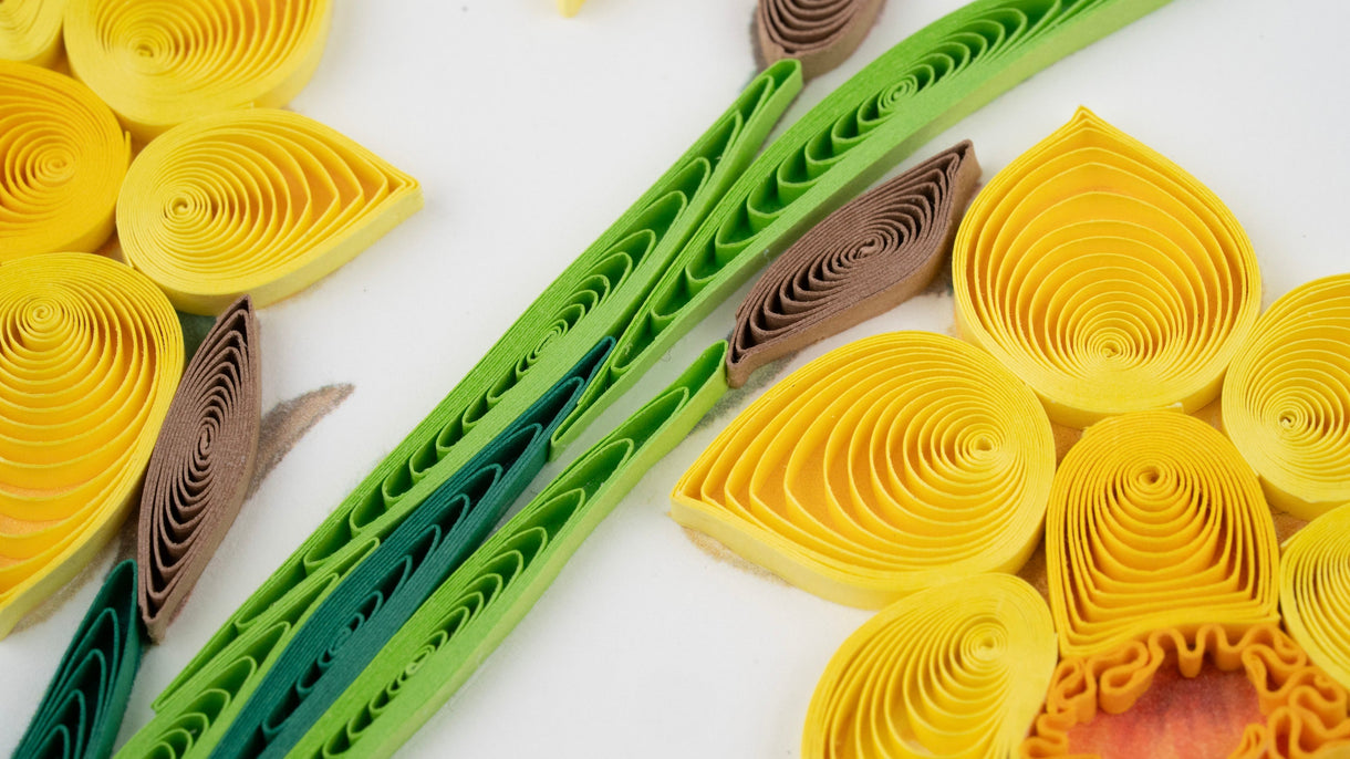 Quilled paper art in yellow, green, and brown on a white background